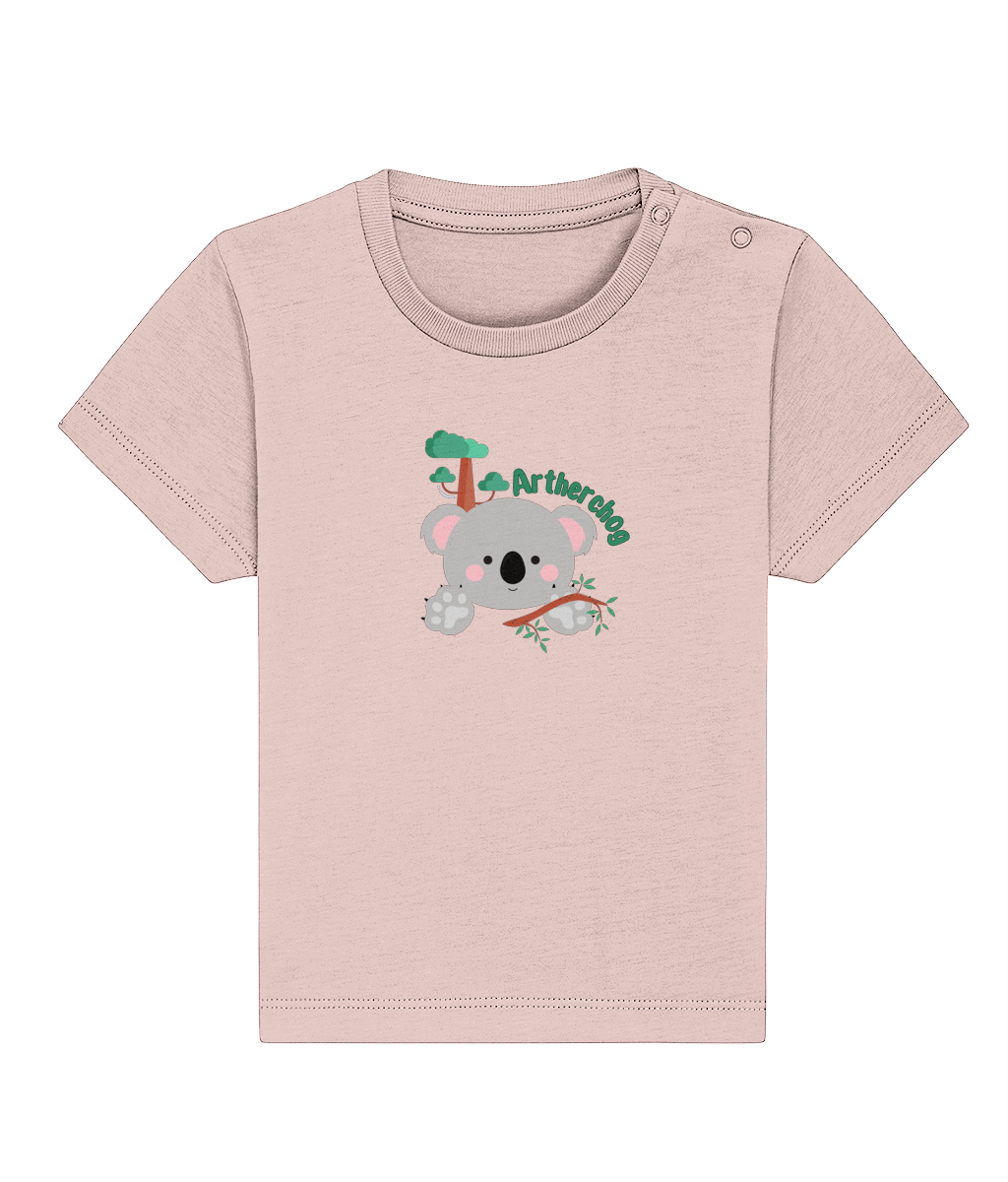 A pink baby t-shirt with a graphic of a koala and a Welsh slogan, made from organic ringspun combed cotton.