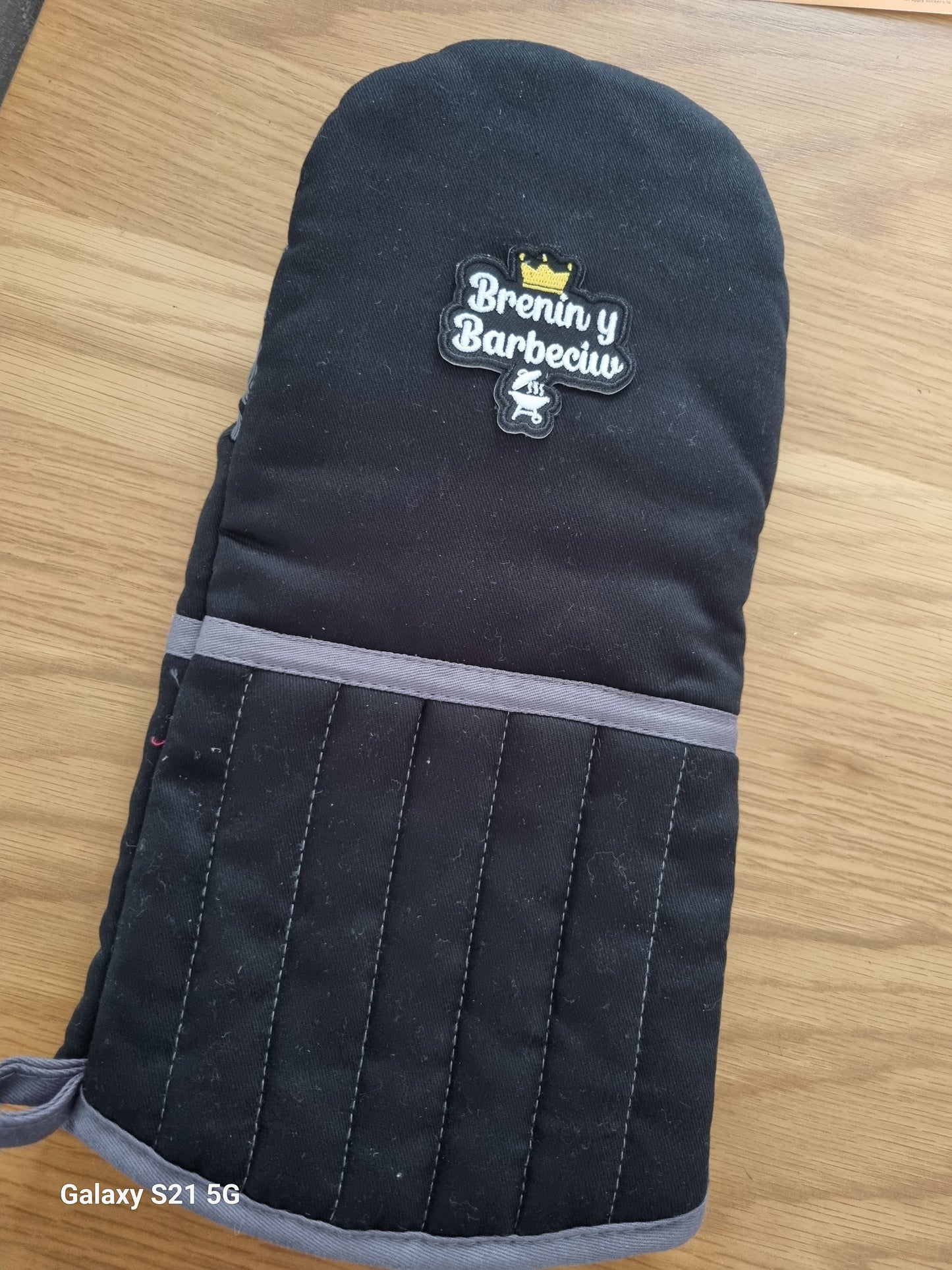 Black oven mitt with a brand logo on a wooden surface
