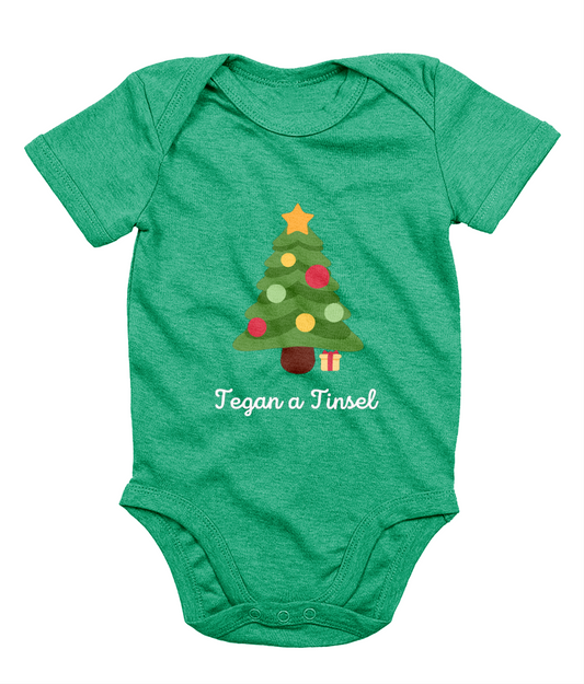 Green Welsh Christmas-themed babygrow with a Christmas tree and gifts design, and the text 'Tegannau a Tinsel' printed on the front.