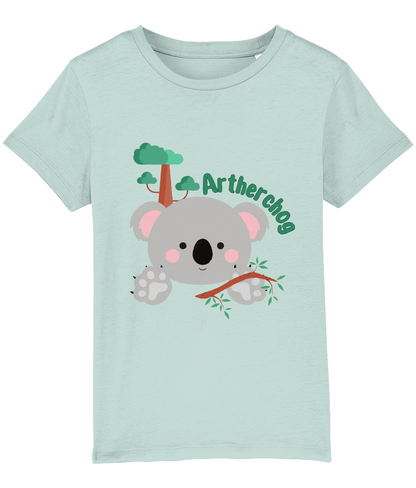 Children's t-shirt with a graphic of a koala bear and the text 'Artherchog'. The t-shirt is blue, and the graphic includes a small green tree.