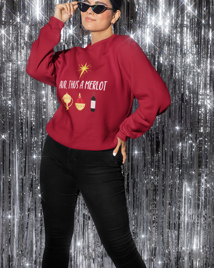 A person wearing a red Christmas sweatshirt with the text 'Aur, Thus a Merlot' and embroidered details, standing against a sparkling background.