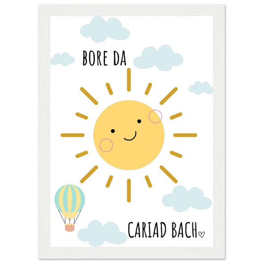 A colorful framed poster featuring a smiling sun with the Welsh phrase 'Bore Da Cariad Bach' and a small hot air balloon.
