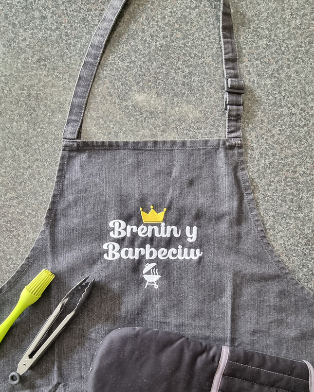 Gray apron with BBQ tools on a stone surface