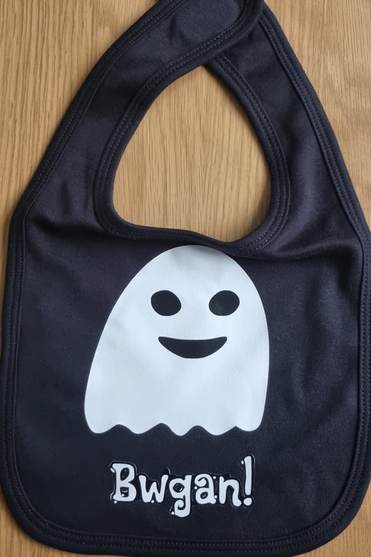 A black cotton bib with a white ghost illustration and the Welsh word 'Bwgan!' printed on it.