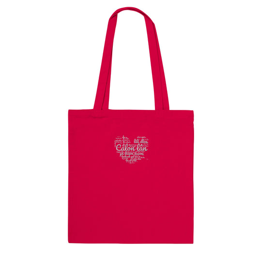A red cotton tote bag with 'Calon Lân' embroidered on the front, featuring Welsh text within a heart shape.