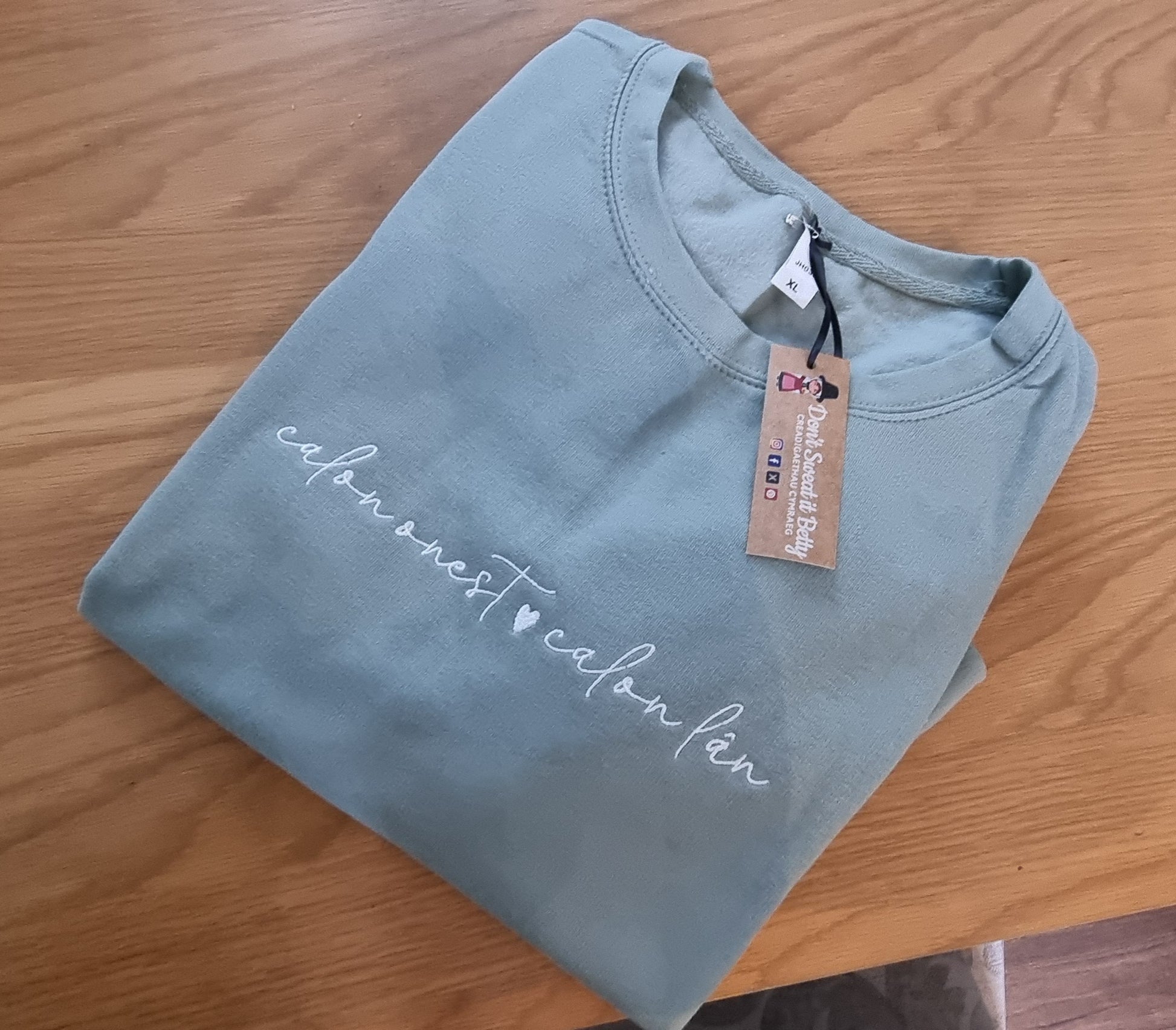 Folded green sweatshirt with calon lan embroidered in white