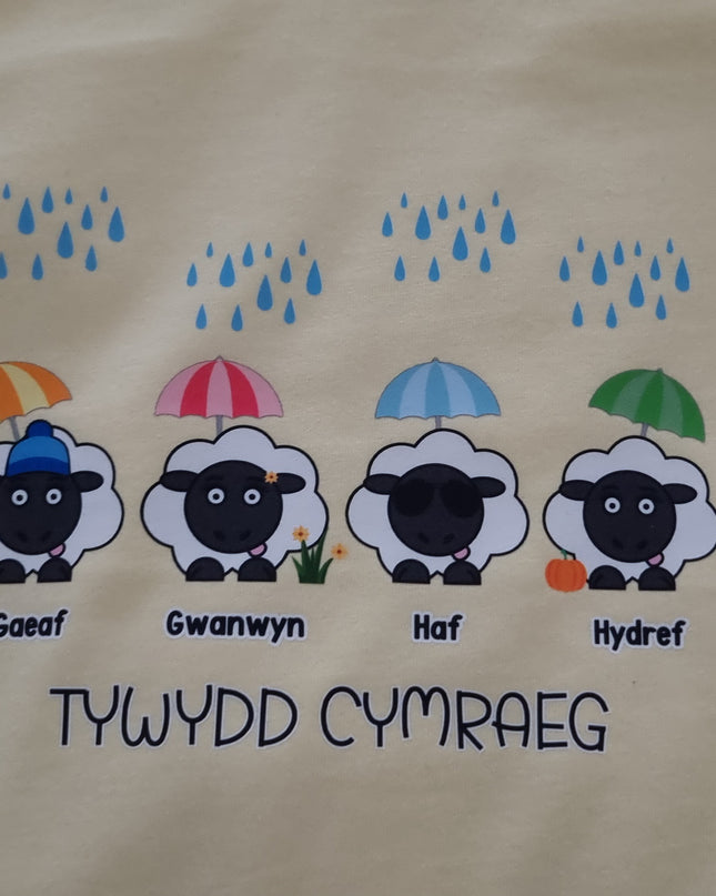 Yellow t-shirt with cartoon sheep and umbrellas on a plain background