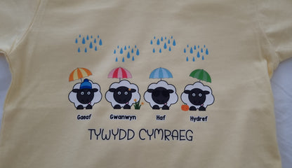 Yellow t-shirt with cartoon sheep and umbrellas on a plain background