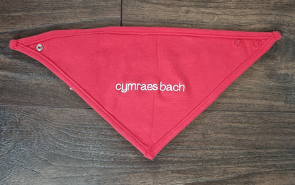 Red bandana cotton bib with 'cymraes bach' text on a wooden surface