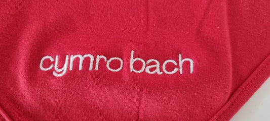 Red fabric with 'cymro bach' embroidered on it