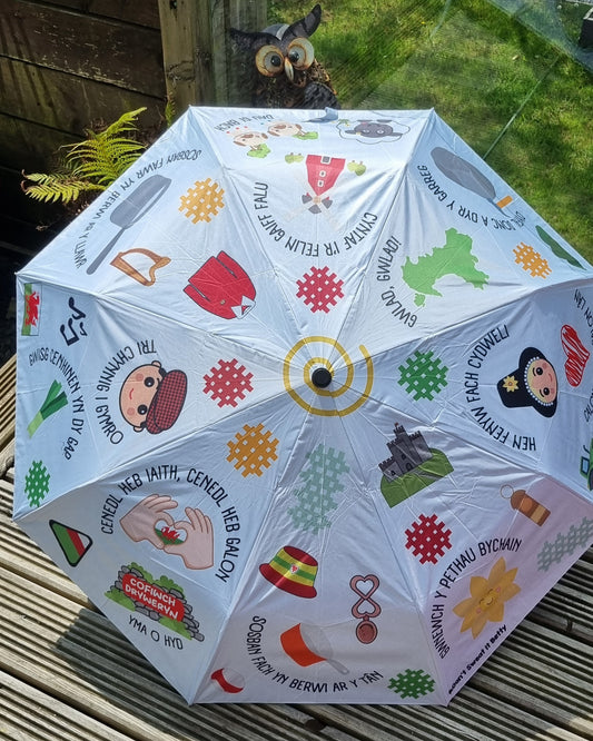 Umbrella with colorful designs and text on a wooden surface