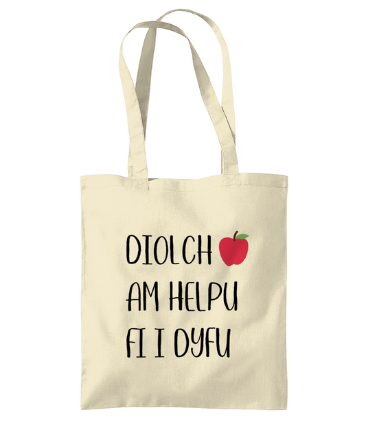 A beige cotton tote bag with the text 'Diolch am helpu fi i dyfu' printed in black.