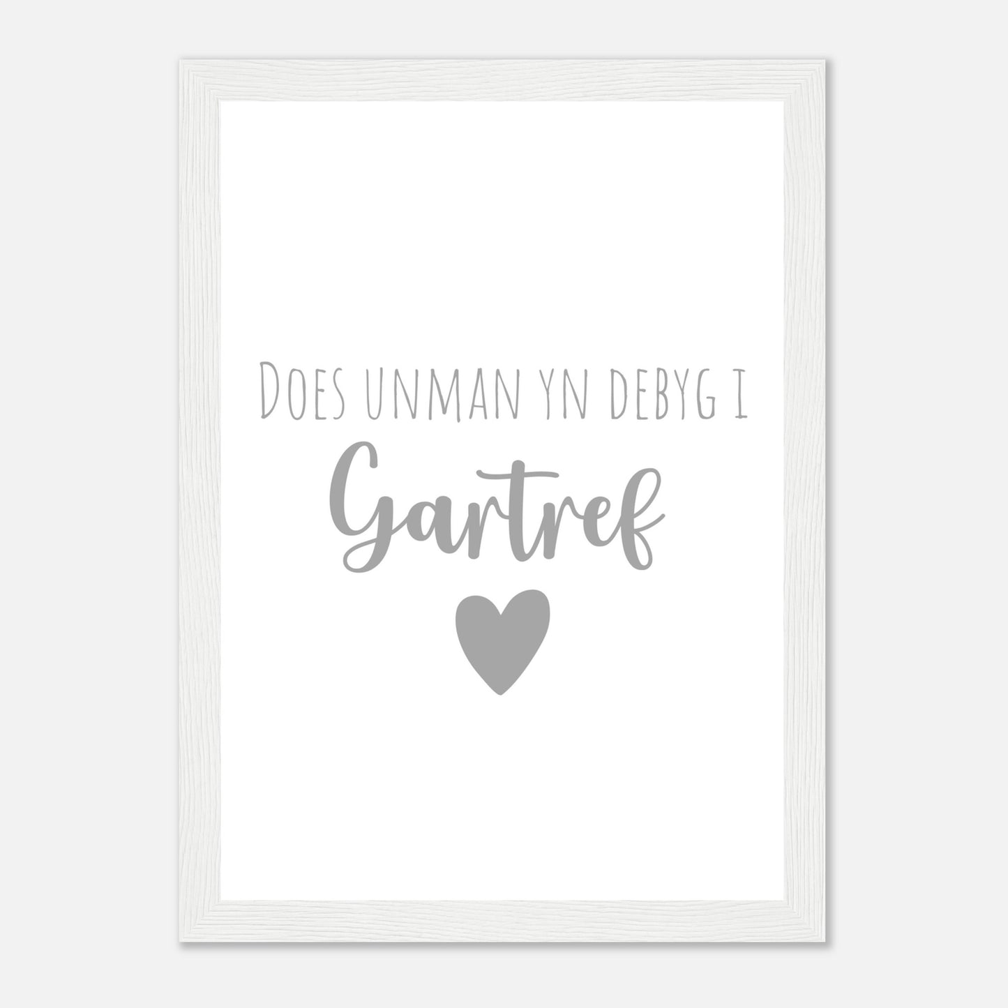 A framed wall art print with the Welsh phrase 'Does unman yn debyg i gartref' which translates to 'There's no place like home' in English, featuring a heart symbol.