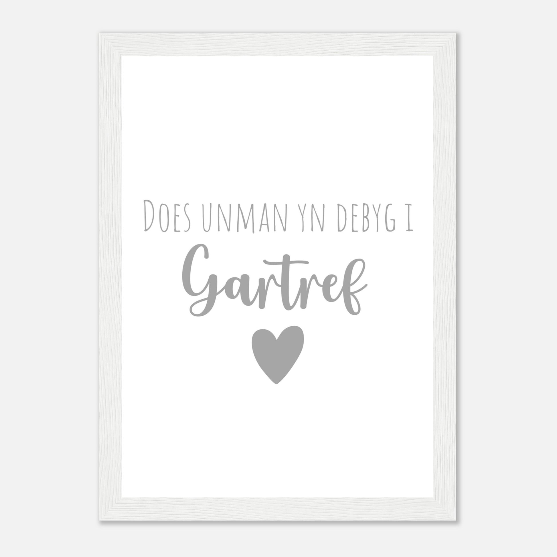 A framed wall art print with the Welsh phrase 'Does unman yn debyg i gartref' which translates to 'There's no place like home' in English, featuring a heart symbol.