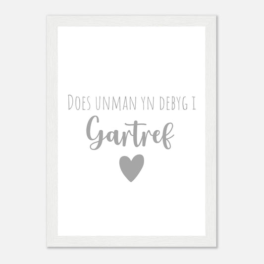 A framed wall art print with the Welsh phrase 'Does unman yn debyg i gartref' which translates to 'There's no place like home' in English, featuring a heart symbol.
