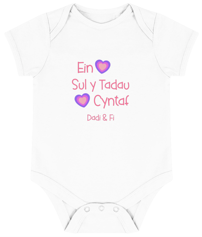 Pink babygrow with the text 'Ein Sul y Tadau Cyntaf' and hearts, translates to 'Our First Father's Day'.