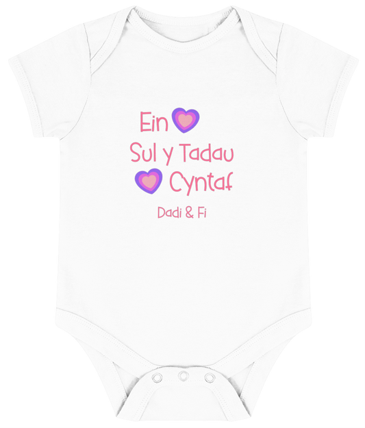 Pink babygrow with the text 'Ein Sul y Tadau Cyntaf' and hearts, translates to 'Our First Father's Day'.
