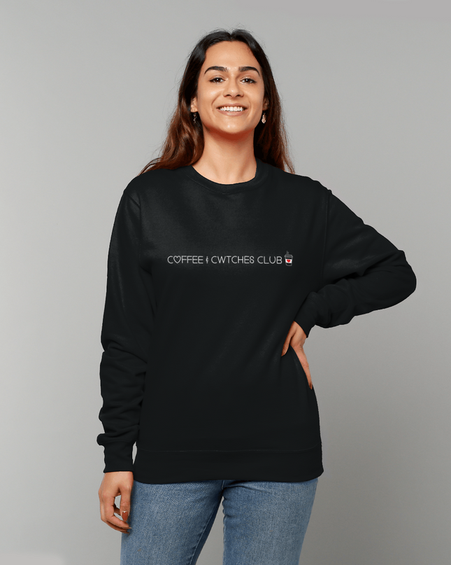 Woman wearing a black sweatshirt with text, standing against a gray background