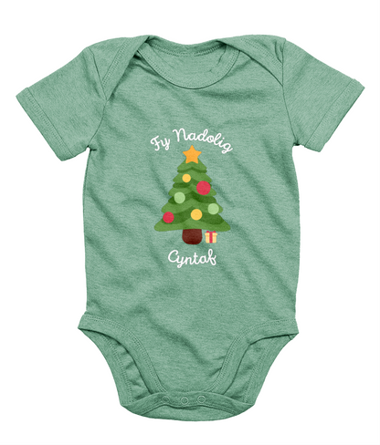 A green babygro with 'Fy Nadolig Cyntaf' printed in Welsh, featuring a Christmas tree motif.