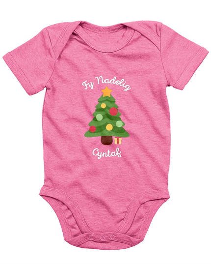 A pink babygro with 'Fy Nadolig Cyntaf' printed in Welsh, featuring a Christmas tree motif.