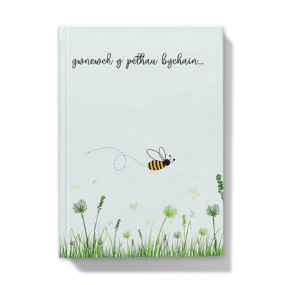 Hardback journal with a illustration of a bee and flowers on the cover, titled 'gwnewch y pethau bychain...' in Welsh.