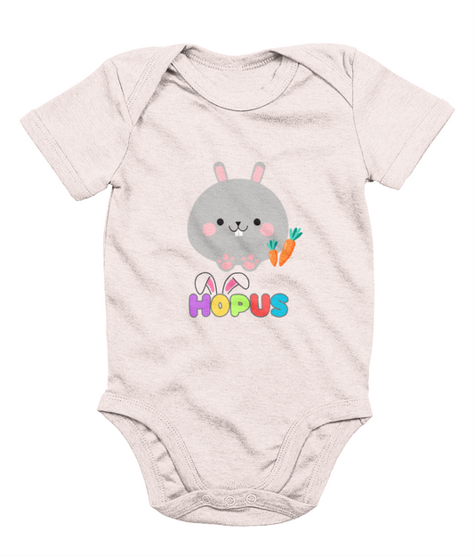 A pink babygrow with a graphic of a grey bunny and the text 'HOPUS' in bold, stylized lettering. The bunny has ears and carrots, suggesting a playful, Easter-themed design.