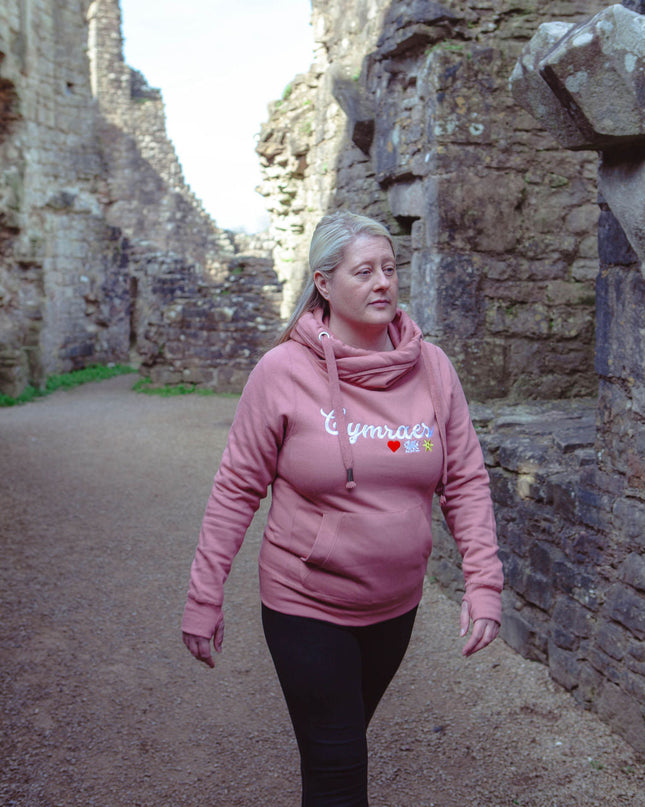 Woman in a pink hoodie walking through stone ruins