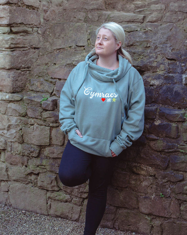 Person wearing a light blue hoodie leaning against a stone wall.