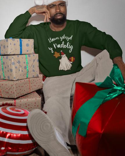 A person wearing a Christmas sweatshirt with a playful design of a ghost wrapped in festive gear, sitting among Christmas decorations.