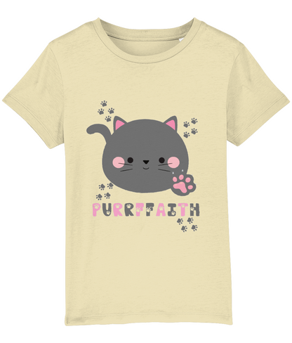 A light-colored girls' t-shirt with a graphic of a cartoon cat and the text 'Purrffaith'. The shirt is designed for children and is organic cotton.