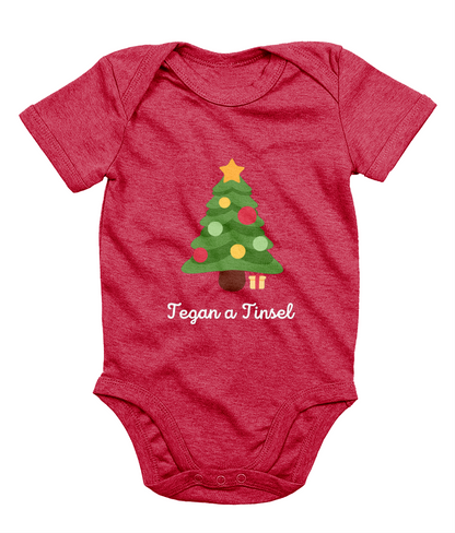 Red Welsh Christmas-themed babygrow with a Christmas tree and gifts design, and the text 'Tegannau a Tinsel' printed on the front.