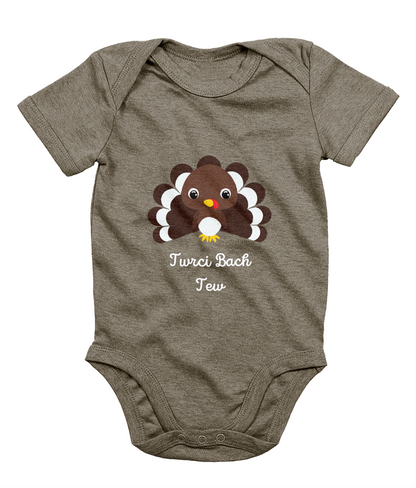 A gray Welsh babygrow with a festive design featuring a character resembling a turkey and the text 'Twrci Bach Tew'.