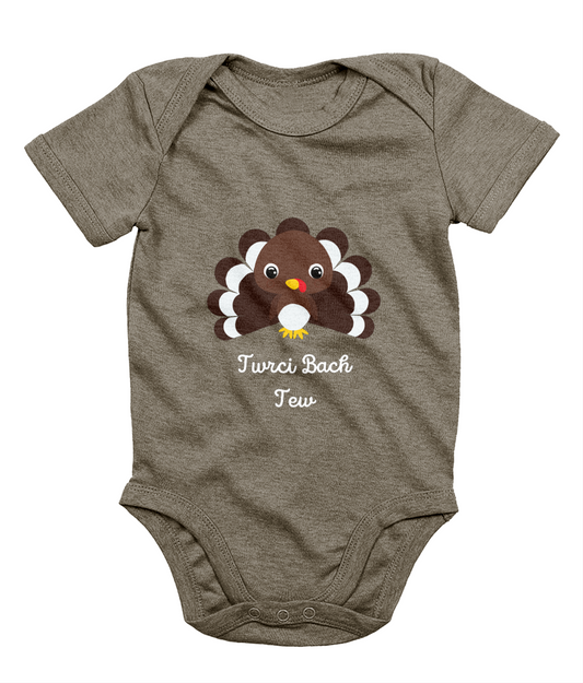 A gray Welsh babygrow with a festive design featuring a character resembling a turkey and the text 'Twrci Bach Tew'.