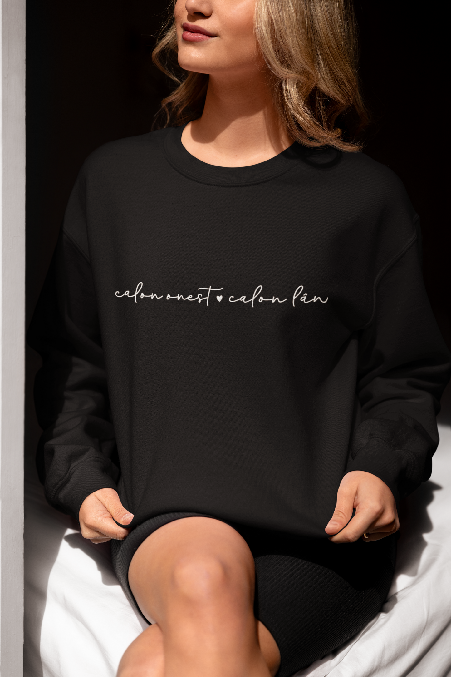 A woman smiling and wearing a black sweatshirt with the embroidered text 'calon onest calon lan' in white.