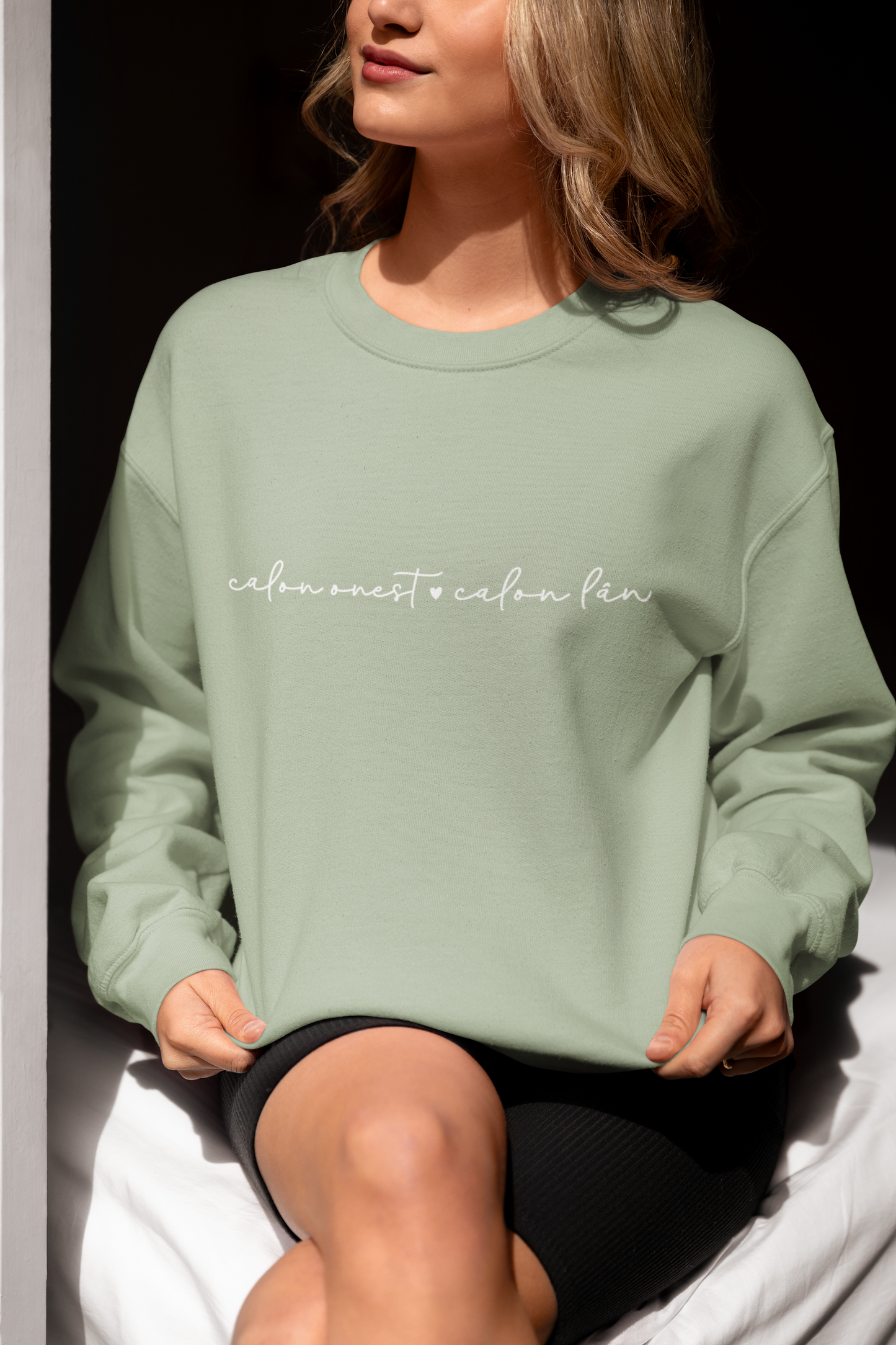 A woman smiling and wearing a green sweatshirt with the embroidered text 'calon onest é calon lan' in white.
