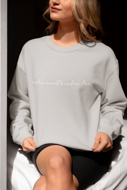 A woman smiling and wearing a grey sweatshirt with the embroidered text 'calon onest calon lan' in white.