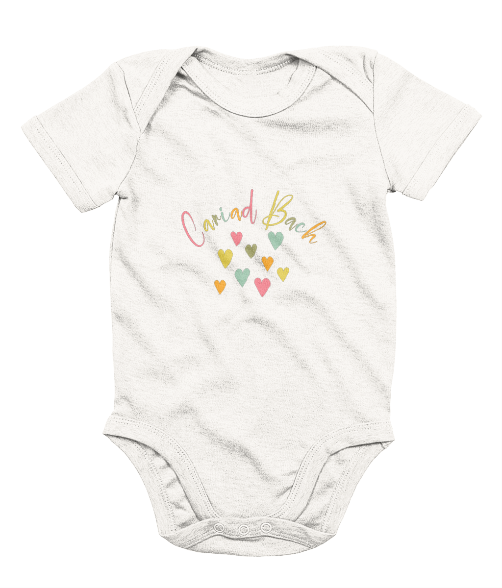 A white babygrow with 'Cariad Bach' text and colorful heart design in the center.