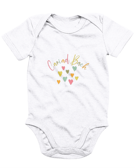 A white babygrow with 'Cariad Bach' text and colorful heart design in the center.