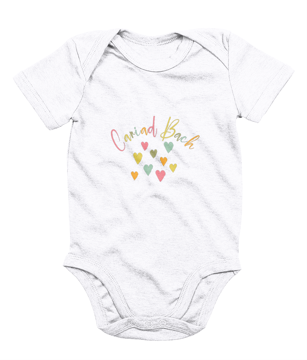 A white babygrow with 'Cariad Bach' text and colorful heart design in the center.