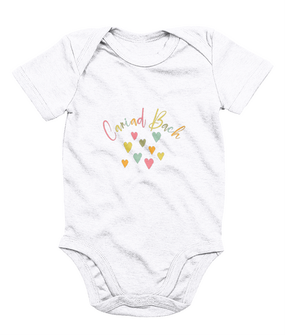 A white babygrow with 'Cariad Bach' text and colorful heart design in the center.