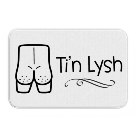 A white rectangular bath mat with a cartoon illustration of a peachy naked bottom and the text 'Ti'n Lysh' in Welsh.